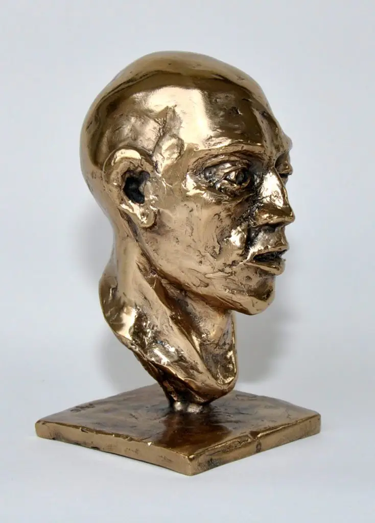 A relatively front facing image of the bronze statue of a bald man head